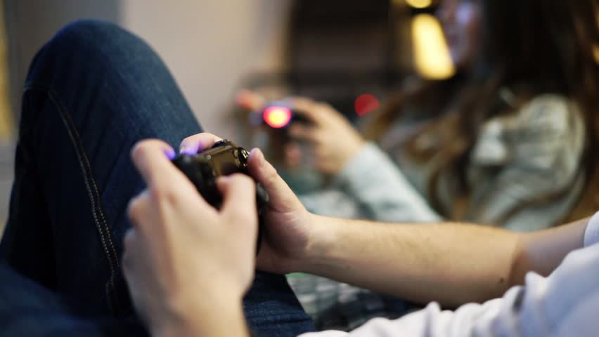 A couple sits and plays a video game together.